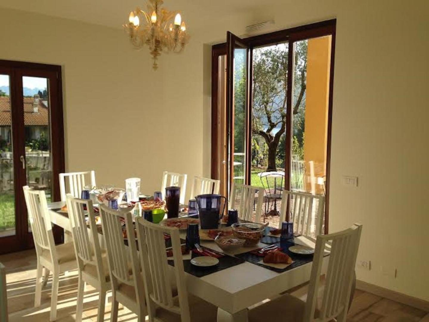 Charming Bellagio Boutique Hotel – sala de mic dejun cu masa lunga, scaune albe si ferestre cu vedere la gradina cu maslin, Bellagio Charming Bellagio Boutique Hotel – sala de mic dejun cu masa lunga, scaune albe si ferestre cu vedere la gradina cu maslin, Bellagio