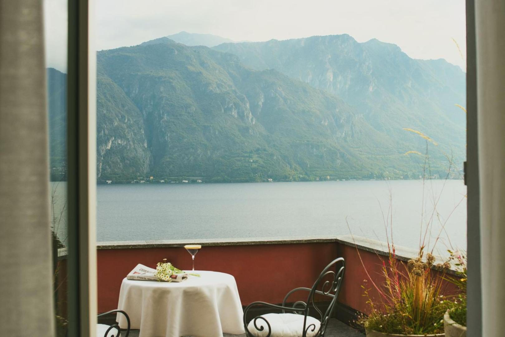 Hotel Belvedere – terasa cu masa, pahar de vin si vedere panoramica la Lacul Como si Alpi Hotel Belvedere – terasa cu masa, pahar de vin si vedere panoramica la Lacul Como si Alpi