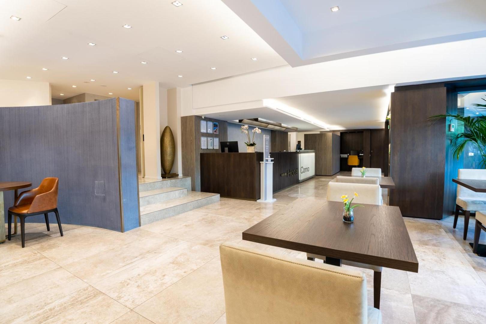 Hotel Como – receptie moderna cu podea din marmura, mobilier din lemn inchis si zona de bar in fundal Hotel Como – receptie moderna cu podea din marmura, mobilier din lemn inchis si zona de bar in fundal