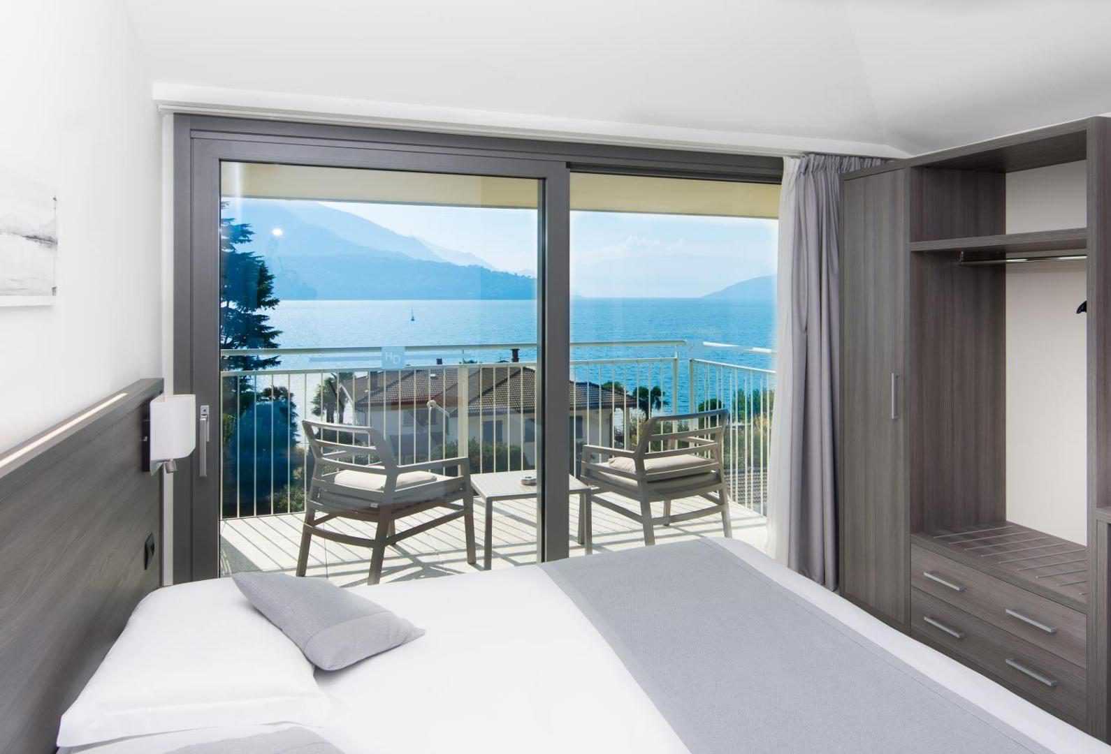 Hotel Domaso – cameră cu pat dublu și ușă glisantă spre balcon cu vedere la Lacul Como Hotel Domaso – cameră cu pat dublu și ușă glisantă spre balcon cu vedere la Lacul Como