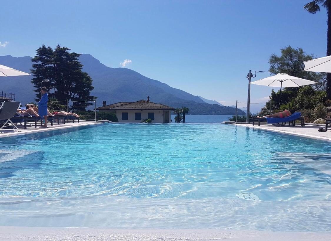 Hotel Domaso – piscina sezonieră cu umbrele albe, șezlonguri și vedere la Lacul Como și Alpi Hotel Domaso – piscina sezonieră cu umbrele albe, șezlonguri și vedere la Lacul Como și Alpi
