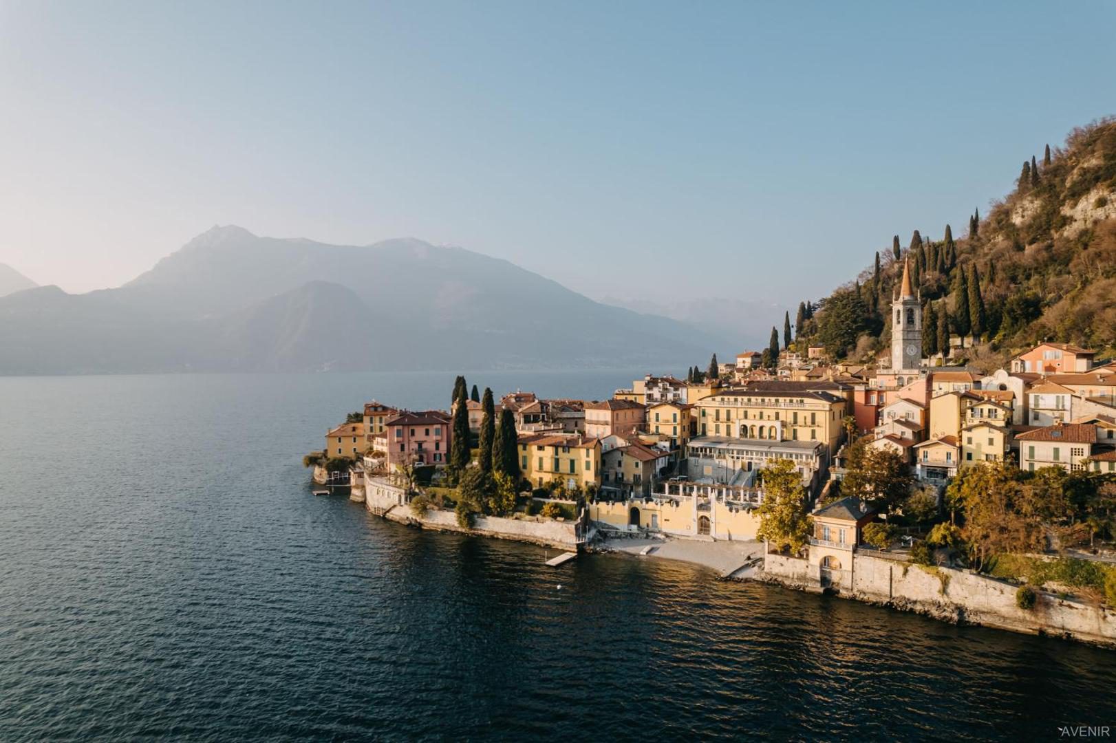 Hotel Royal Victoria Varenna – vedere aeriana a orasului Varenna cu cladiri colorate, turn de biserica, chiparosi si Lacul Como si muntii in fundal Hotel Royal Victoria Varenna – vedere aeriana a orasului Varenna cu cladiri colorate, turn de biserica, chiparosi si Lacul Como si muntii in fundal