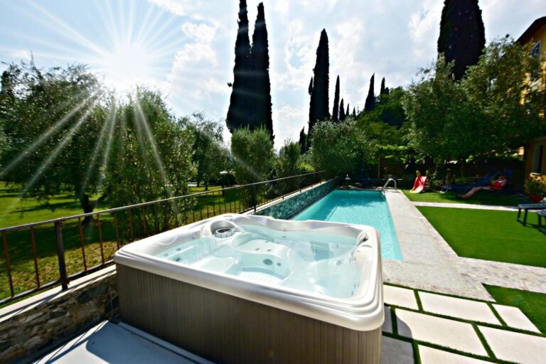 Hotel Diffuso Il Portichetto Perledo – jacuzzi exterior pe terasa de piatra, piscina sezoniera si gradina cu chiparosi in fundal sub raze de soare, Perledo, Lacul Como