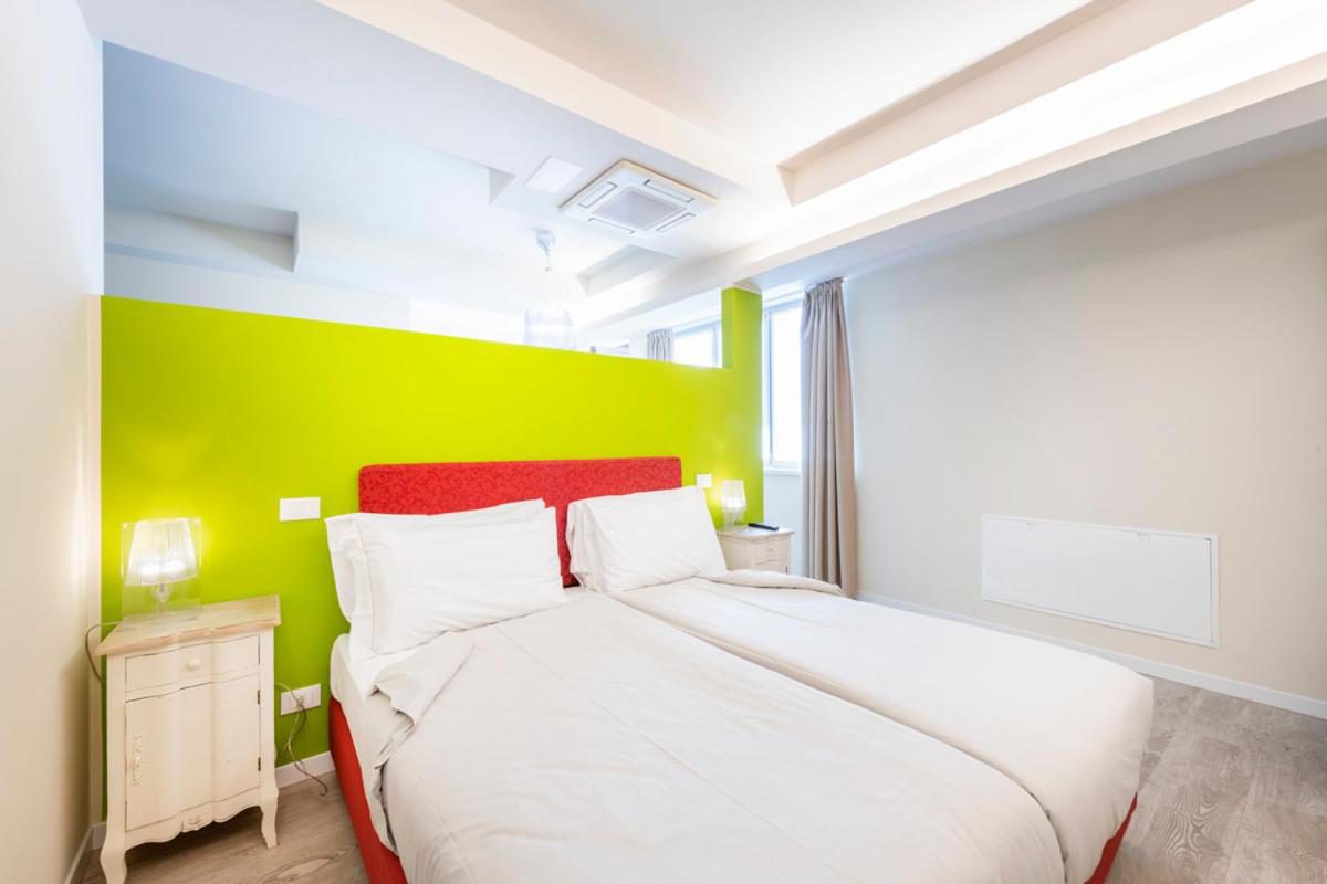 Residence Lenno – dormitor cu perete verde lime, pat dublu si cadru rosu, noptiera vintage, Lenno Residence Lenno – dormitor cu perete verde lime, pat dublu si cadru rosu, noptiera vintage, Lenno