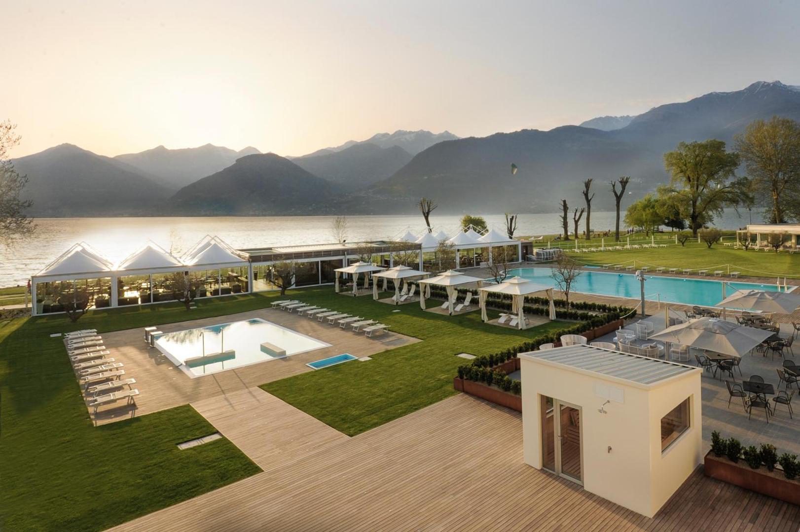 Seven Park Hotel – doua piscine exterioare sezoniere cu sezlonguri si pavilion alb, direct pe malul Lacului Como la apus, Colico Seven Park Hotel – doua piscine exterioare sezoniere cu sezlonguri si pavilion alb, direct pe malul Lacului Como la apus, Colico