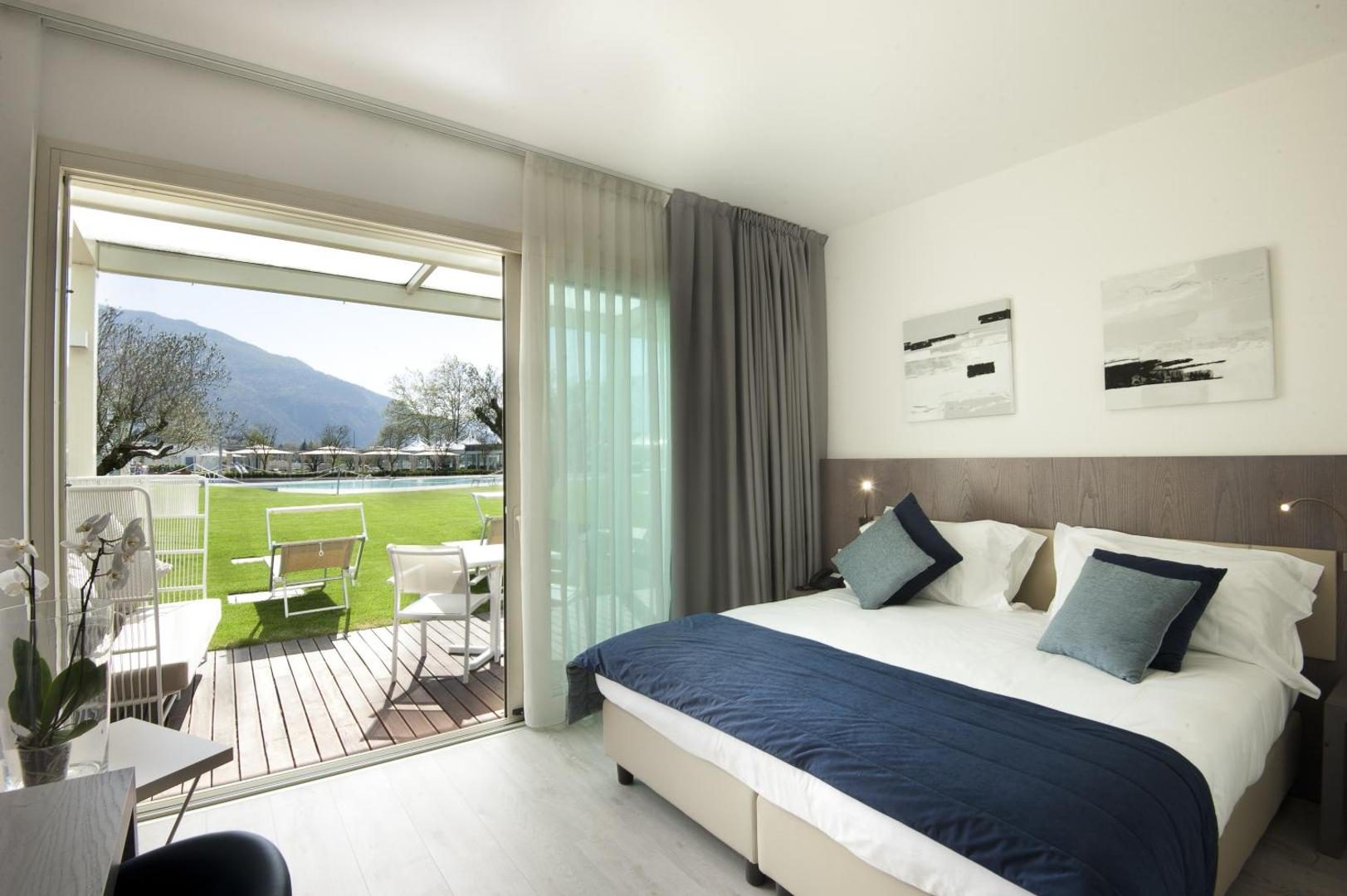 Seven Park Hotel – camera dubla moderna cu pat albastru-navy si usa glisanta spre terasa cu vedere la piscina si munti, Colico Seven Park Hotel – camera dubla moderna cu pat albastru-navy si usa glisanta spre terasa cu vedere la piscina si munti, Colico