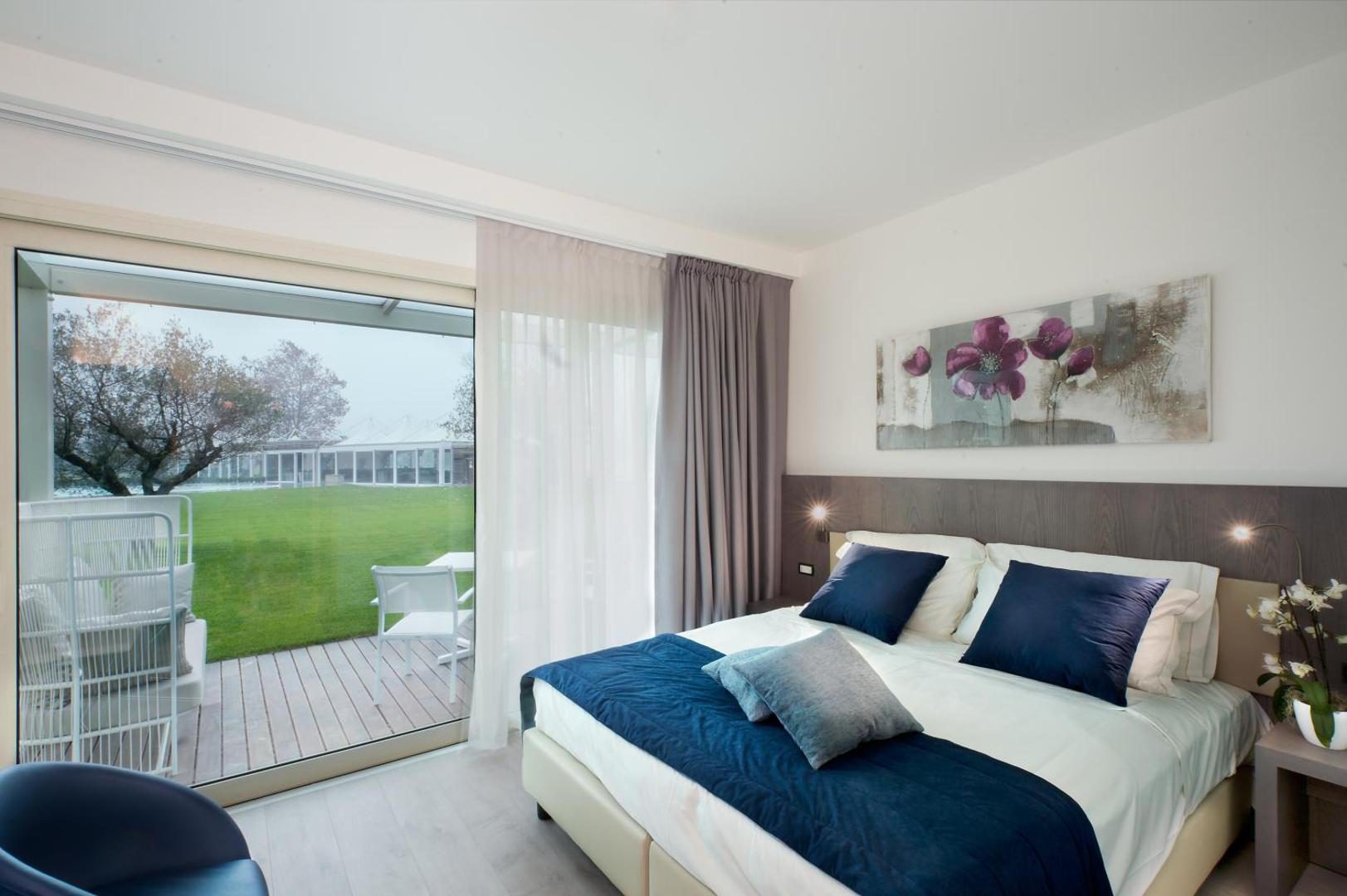 Seven Park Hotel – camera dubla eleganta cu pat navy, tablou cu flori si usa spre terasa cu gradina, Colico, Lacul Como Seven Park Hotel – camera dubla eleganta cu pat navy, tablou cu flori si usa spre terasa cu gradina, Colico, Lacul Como