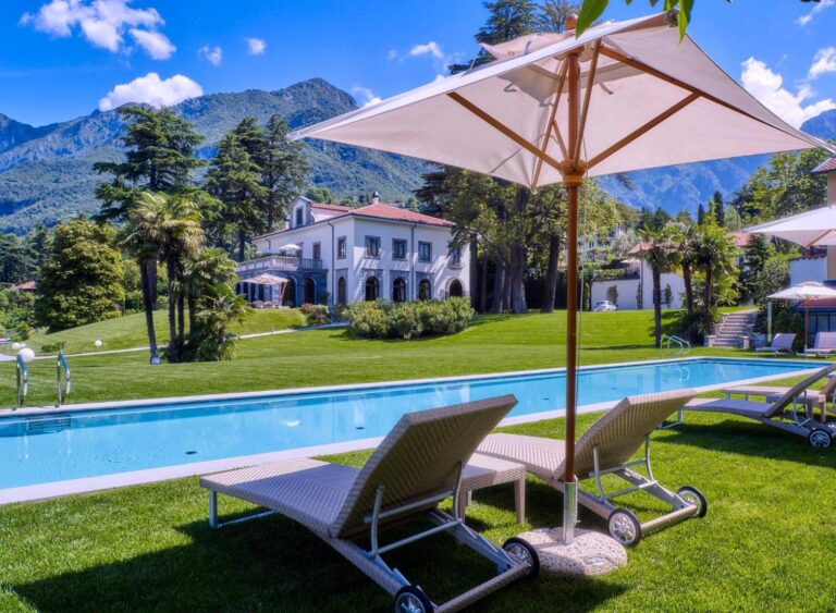 Villa Lario Resort Mandello – piscina exterioara de 20m cu sezlonguri si umbrela, vila alba cu acoperis din tigla si munti in fundal, Mandello del Lario