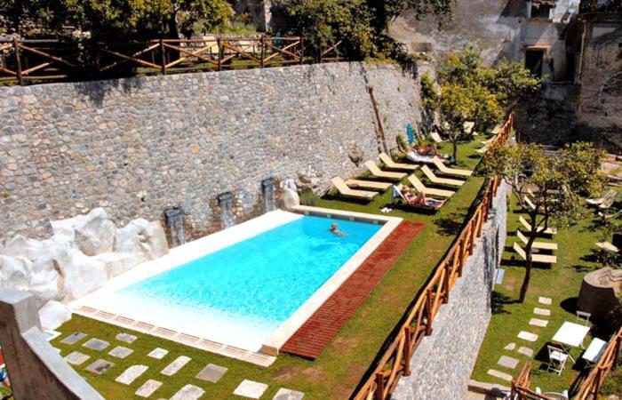Cartiera Apartment Amalfi – piscina comuna cu cascade decorative pe zid de piatra