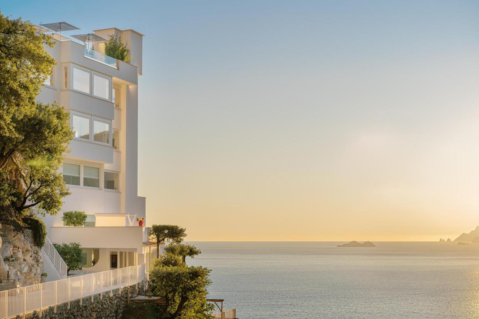 Casa Angelina Praiano – fatada alba minimalista a hotelului la apus, deasupra marii Casa Angelina Praiano – fatada alba minimalista a hotelului la apus, deasupra marii