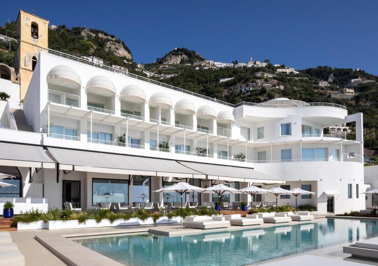 Furore Grand Hotel – fatada alba a hotelului cu balcoane si vedere la satul de pe stanca Furore Grand Hotel – fatada alba a hotelului cu balcoane si vedere la satul de pe stanca