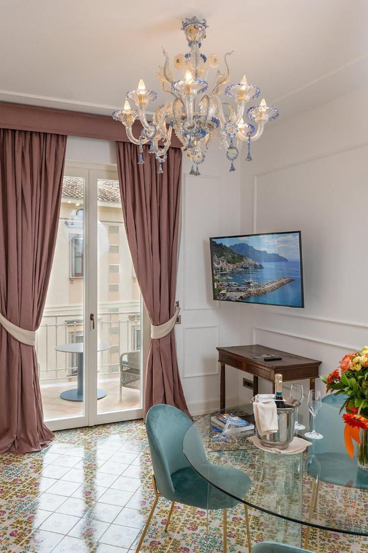 Hotel Marina Riviera Amalfi – living elegant cu candelabru de cristal muranez si masa cu scaune verzi Hotel Marina Riviera Amalfi – living elegant cu candelabru de cristal muranez si masa cu scaune verzi