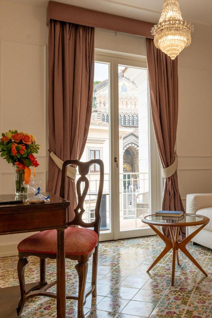 Hotel Marina Riviera Amalfi – living cu candelabru clasic si vedere directa la Catedrala din Amalfi prin fereastra Hotel Marina Riviera Amalfi – living cu candelabru clasic si vedere directa la Catedrala din Amalfi prin fereastra