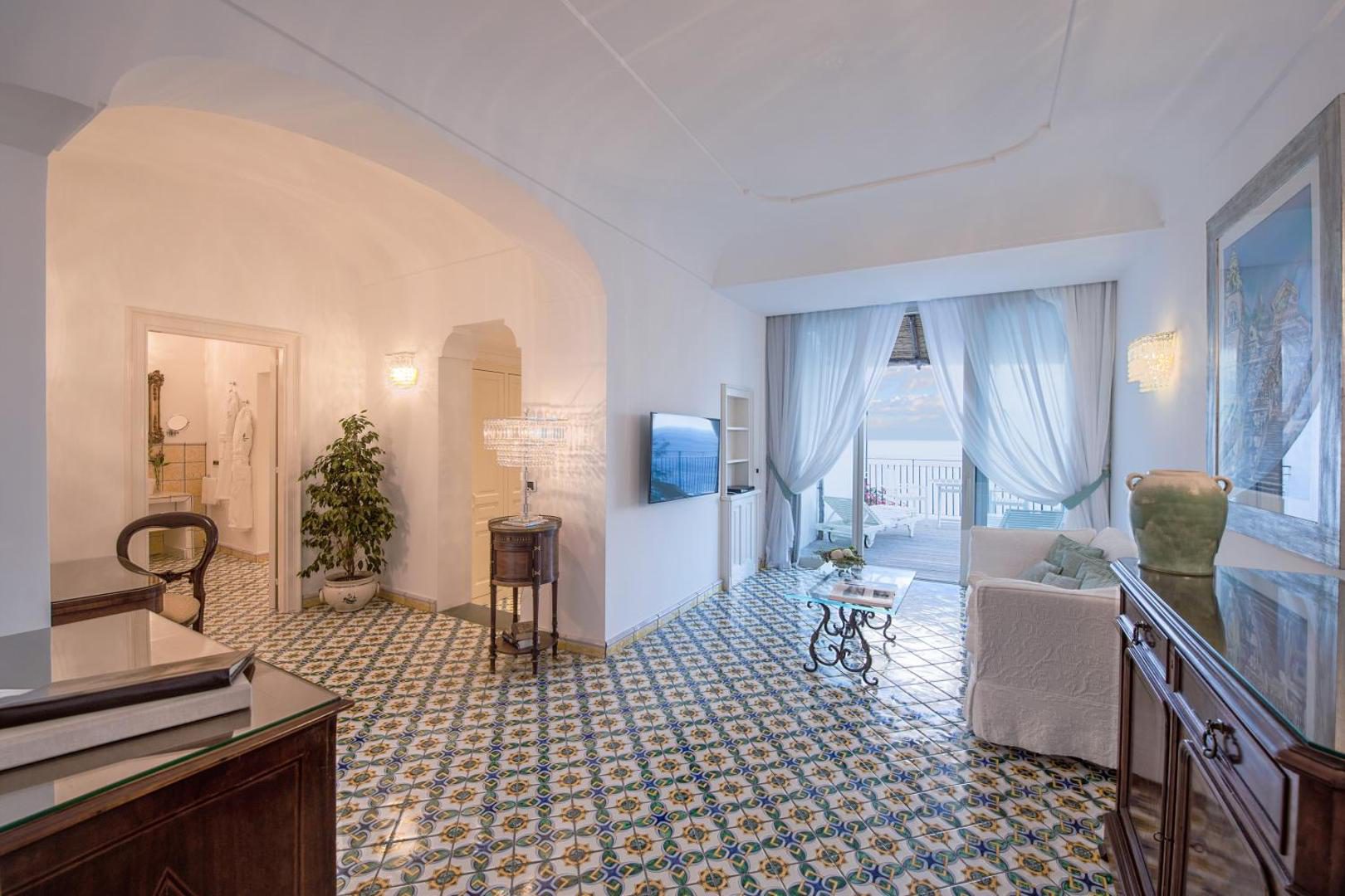 Hotel Santa Caterina Amalfi – dormitor cu tablie florala roz-portocalie si vedere directa la mare prin fereastra Hotel Santa Caterina Amalfi – dormitor cu tablie florala roz-portocalie si vedere directa la mare prin fereastra