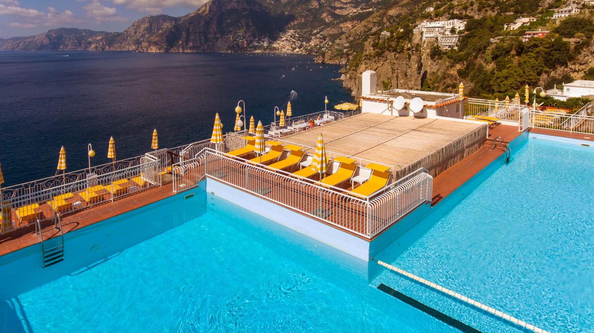 Hotel Tramonto d'Oro Praiano – piscina exterioara pe acoperis cu sezlonguri galbene si vedere panoramica la coasta