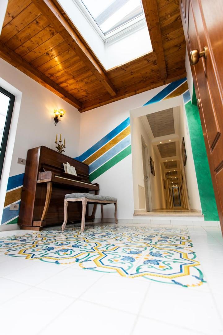 Panariello Palace Agerola – colt cu pian sub tavan de lemn si faianta traditionala pe pardoseala Panariello Palace Agerola – colt cu pian sub tavan de lemn si faianta traditionala pe pardoseala