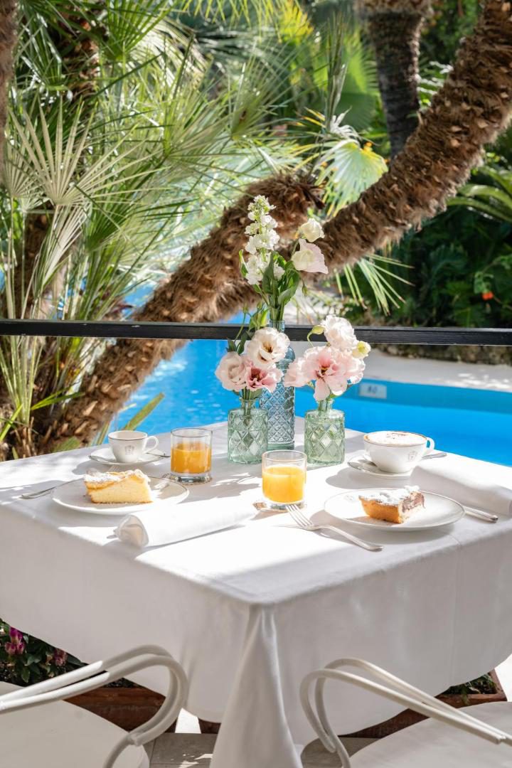 Reginna Palace Hotel Maiori – micul dejun servit langa piscina, cu flori si prajitura Reginna Palace Hotel Maiori – micul dejun servit langa piscina, cu flori si prajitura
