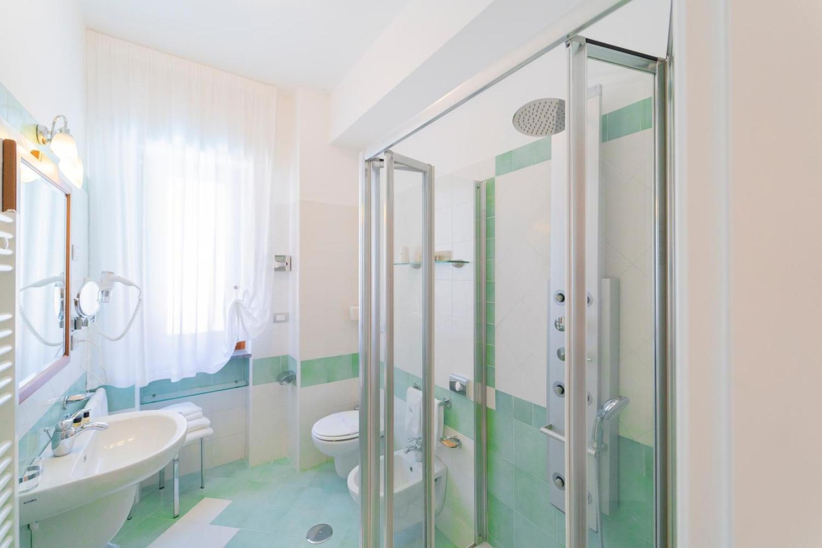 Hotel San Pietro Maiori – baie moderna cu faianta verde si cabina de dus Hotel San Pietro Maiori – baie moderna cu faianta verde si cabina de dus