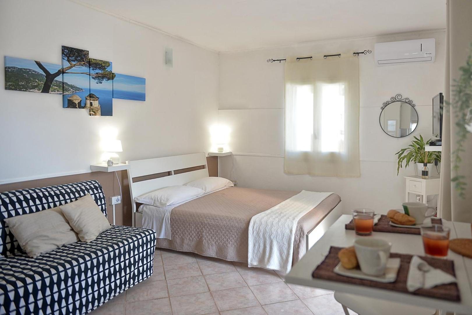 Villa Inn Costa Tramonti – dormitor cu canapea si tablou cu Coasta Amalfitana Villa Inn Costa Tramonti – dormitor cu canapea si tablou cu Coasta Amalfitana