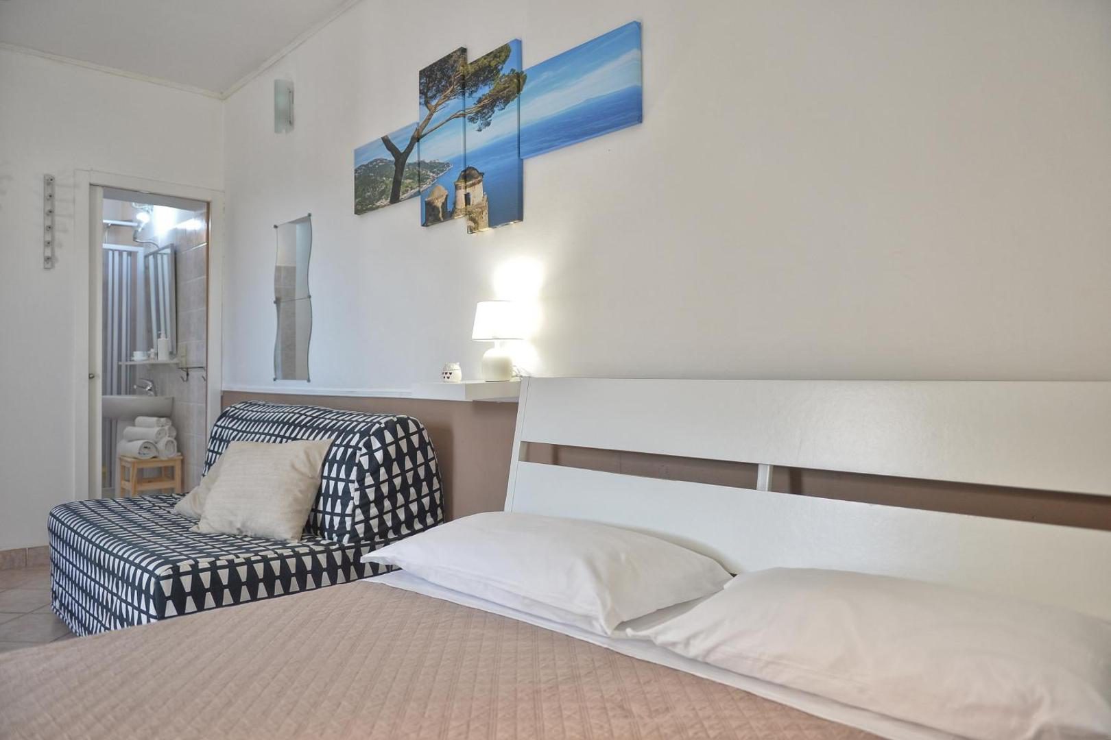 Villa Inn Costa Tramonti – dormitor cu canapea extensibila si tablou cu coasta Villa Inn Costa Tramonti – dormitor cu canapea extensibila si tablou cu coasta