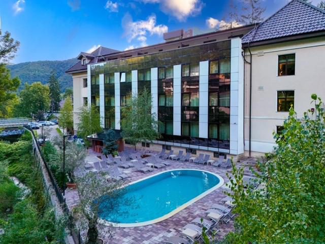 Hotel IZVOARE Caciulata – vedere aeriană asupra hotelului și piscinei exterioare