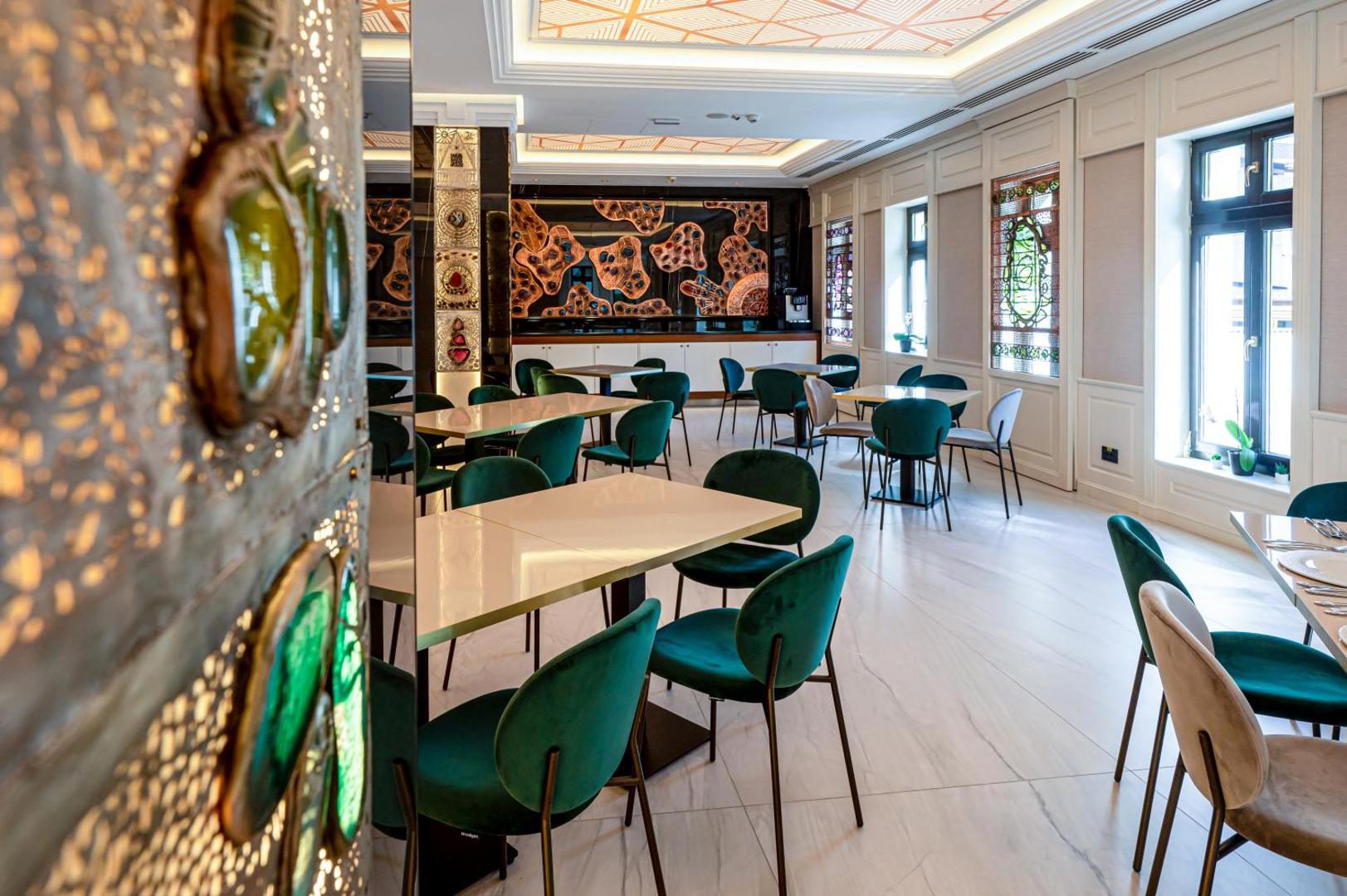 Restaurantul Hotel Carolin, cu vitralii și scaune verzi Restaurantul Hotel Carolin, cu vitralii și scaune verzi