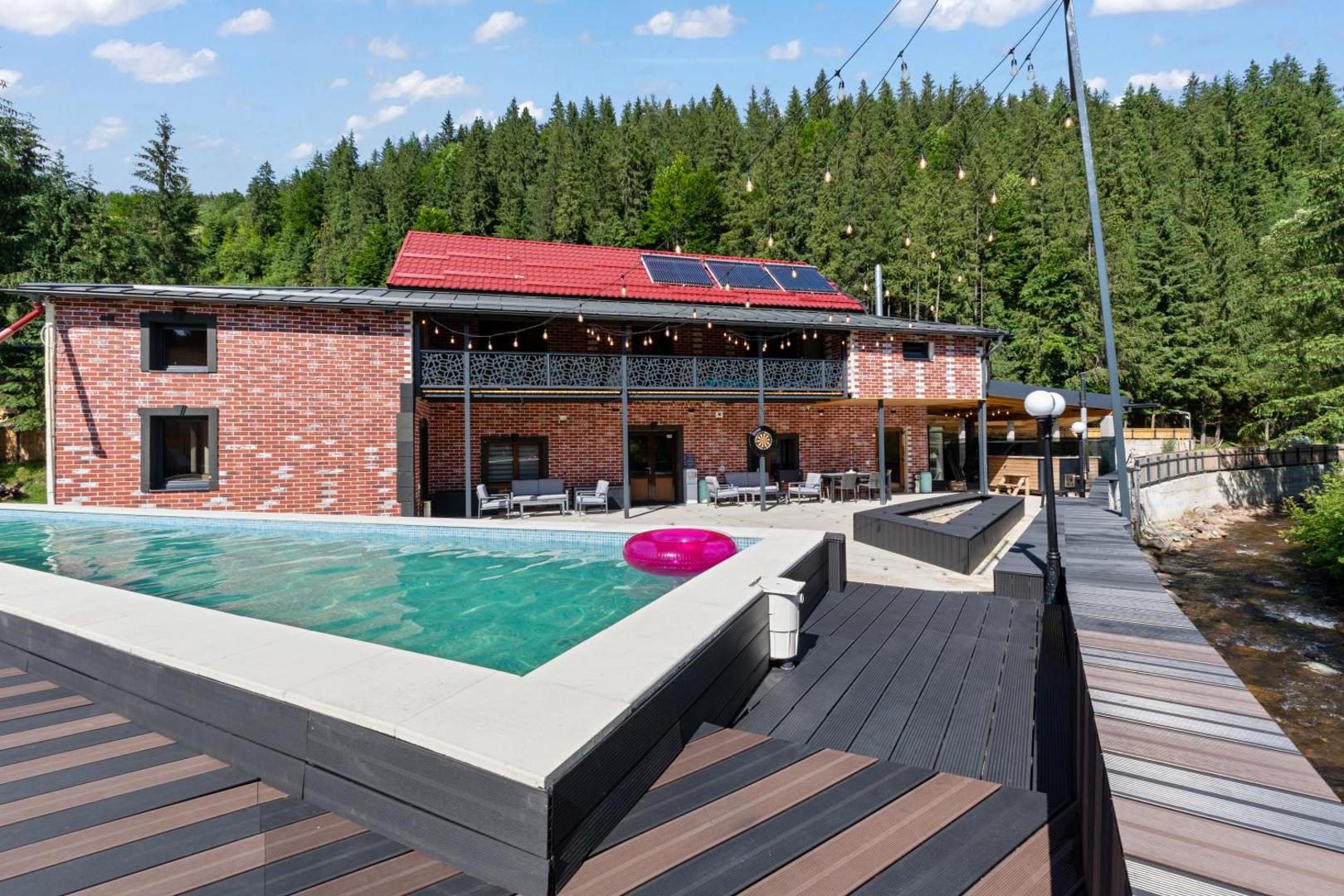 Transylvania House – piscina exterioară și terasa, cu pădurea de brazi în fundal Transylvania House – piscina exterioară și terasa, cu pădurea de brazi în fundal