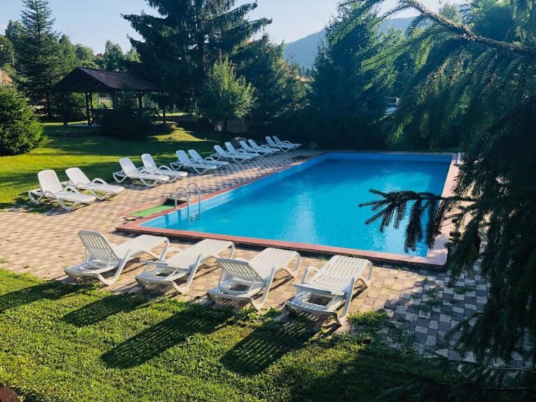 Stanca Soimilor – piscina exterioară cu șezlonguri, înconjurată de brazi