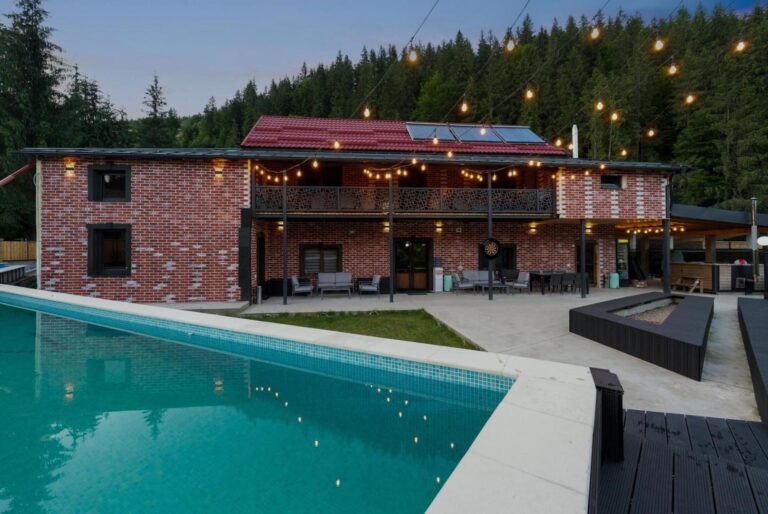 Transylvania House – piscina exterioară încălzită, seara, cu clădirea de cărămidă în fundal